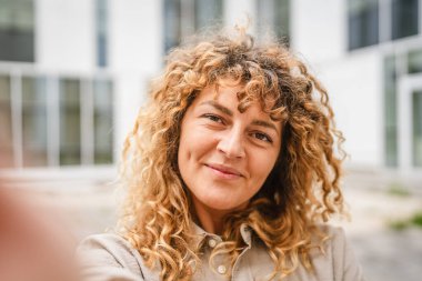 Yetişkin bir kadın cep telefonunu tutar ve kendi portresini çeker.