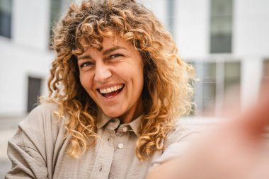 Yetişkin bir kadın cep telefonunu tutar ve kendi portresini çeker.