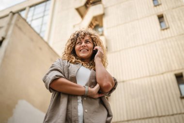 Yetişkin bir kadın işe ara verip ön binadaki cep telefonuyla konuşur.