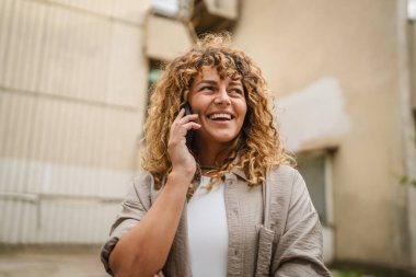 Yetişkin bir kadın işe ara verip ön binadaki cep telefonuyla konuşur.