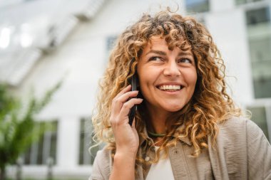 Yetişkin bir kadın işe ara verip ön binadaki cep telefonuyla konuşur.