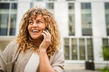 Yetişkin bir kadın işe ara verip ön binadaki cep telefonuyla konuşur.