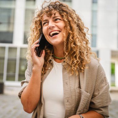 Yetişkin bir kadın işe ara verip ön binadaki cep telefonuyla konuşur.