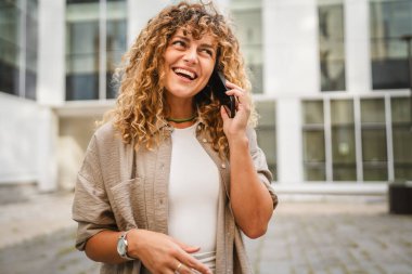 Yetişkin bir kadın işe ara verip ön binadaki cep telefonuyla konuşur.