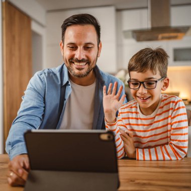 Baba ve oğlunun evdeki tabletle bir video görüşmesi var.