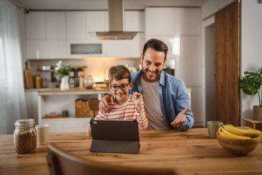 Baba ve oğlunun evdeki tabletle bir video görüşmesi var.