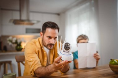 Baba ve oğlu beyaz tenli ev mutfağına bağlanıyor ve güvenlik kamerası yerleştiriliyor.