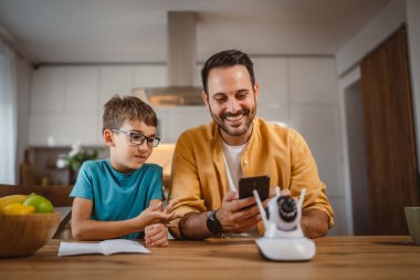 Baba ve oğlu beyaz tenli ev mutfağına bağlanıyor ve güvenlik kamerası yerleştiriliyor.