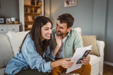 Kocasıyla mutlu hamile kadın, bebeğin ultrason fotoğrafını izliyor.
