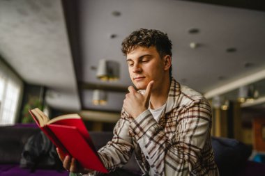 Oturup kitap okuyan genç bir çocuk.