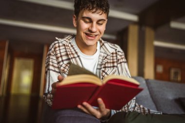 Oturup kitap okuyan genç bir çocuk.