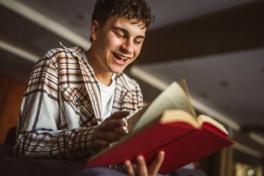 Oturup kitap okuyan genç bir çocuk.