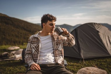 Delikanlı, çadırın önünde otur ve dağda kahve iç.