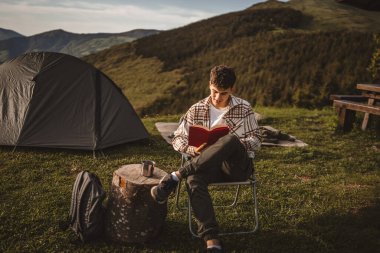 Delikanlı, çadırda otur ve dağda bir kitap oku.