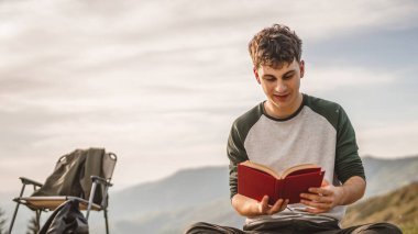 Genç çocuk çadırın önündeki dağda bir kitap okudu.