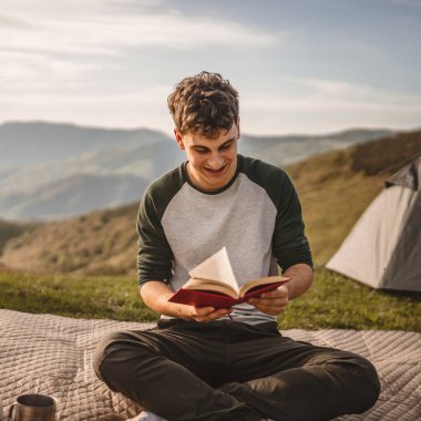 Genç çocuk çadırın önündeki dağda bir kitap okudu.