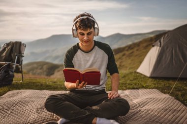 Genç çocuk meditasyon yaptı ve dağda bir kitap okudu.