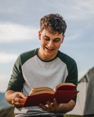 Genç çocuk çadırın önündeki dağda bir kitap okudu.