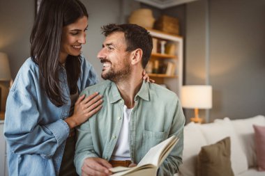 Sevgili koca kitap okurken sevgili eş ona sarılır aşk, mutluluk