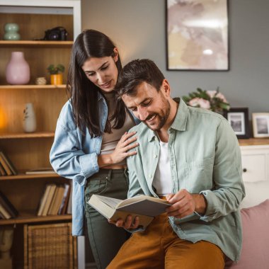 Sevgili koca kitap okurken sevgili eş ona sarılır aşk, mutluluk