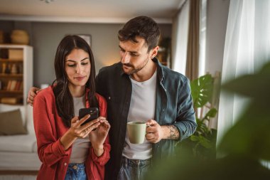 Çift, kahve fincanlarını tutarken cep telefonunu mesaj atmak ya da internette gezinmek için kullanır