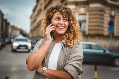 Yetişkin, güzel bir kadın sokakta cep telefonu standında konuşuyor.