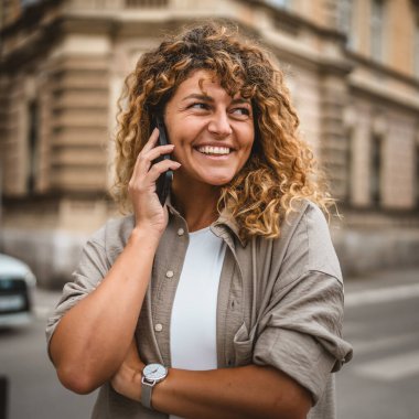 Yetişkin, güzel bir kadın sokakta cep telefonu standında konuşuyor.