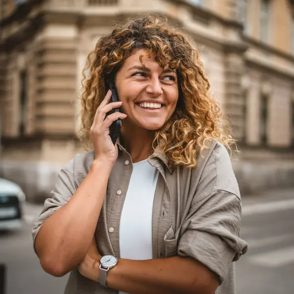 Yetişkin, güzel bir kadın sokakta cep telefonu standında konuşuyor.
