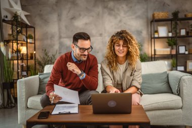 İki iş arkadaşı evde dizüstü bilgisayarda birlikte çalışıyorlar.