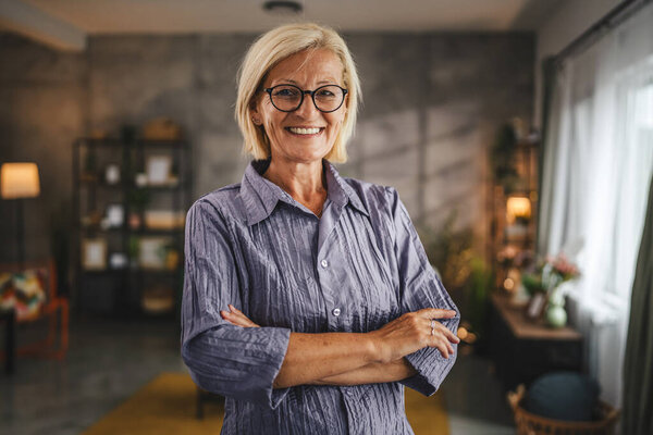 Portrait of beautiful mature senior woman stand and smile at home