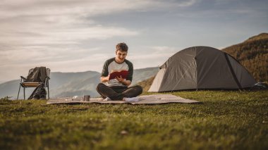 Genç çocuk çadırın önündeki dağda bir kitap okudu.
