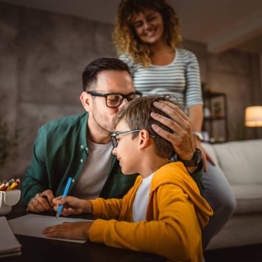 Üç kişilik mutlu bir aile, ödevlerini evde bir defterde yapıyor.