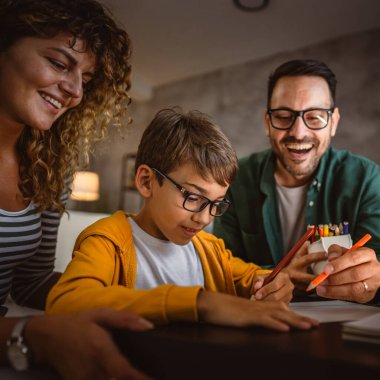 Üç kişilik mutlu bir aile, ödevlerini evde bir defterde yapıyor.