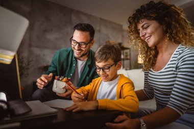 Üç kişilik mutlu bir aile, ödevlerini evde bir defterde yapıyor.