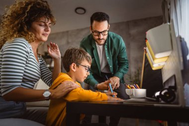 Üç kişilik mutlu bir aile, ödevlerini evde bir defterde yapıyor.