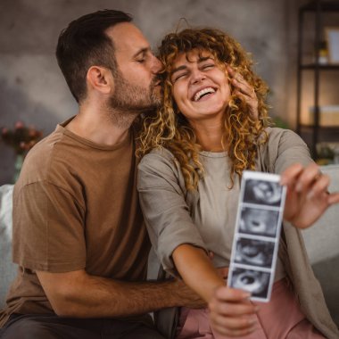 Çift karı koca oturur ve bebeğin ultrason fotoğrafını tutarlar.