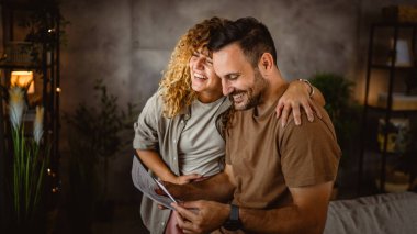 Kadın, bebeğinin ultrason fotoğrafına bakarken kocasına sarılır.
