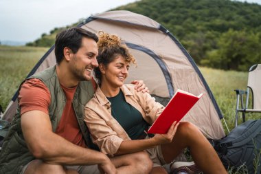Kız arkadaşı erkek arkadaşıyla çadırın önünde kitap okudu.