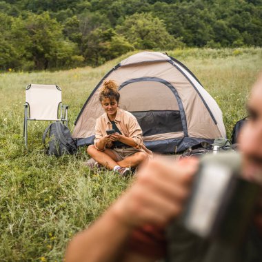 Kız arkadaş kampın önünde cep telefonu kullanıyor.