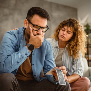 Stresli çift oturur ve istenmeyen bebeğin ultrason fotoğrafı hakkında konuşur.