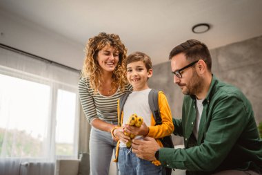 Anne ve baba, oğlana evdeki ilk gün okulu için sırt çantası ve atıştırmalık için yardım ediyor.