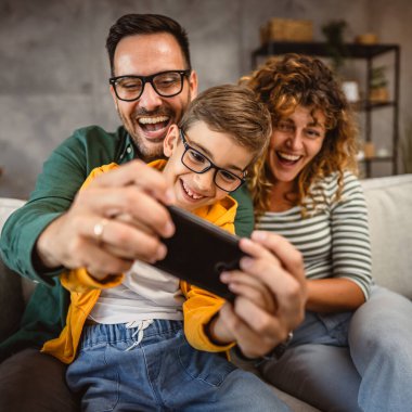 Anne, baba ve oğul evde cep telefonuyla oyun oynuyorlar.