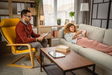 Psikoterapist ağlayan kadın müşteriyi dinler ve panoya yazar.