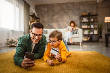 Anne ve baba kredi kartı ve cep telefonuyla online alışveriş yapıyorlar.