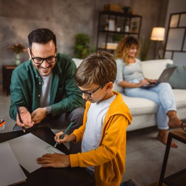 Baba ödevini yap, oğul çiz anne arka planda çalışırken.