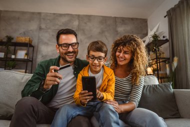 Anne, baba ve oğul internet üzerinden kredi kartıyla alışveriş yapıyorlar.