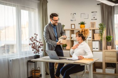 Erkek meslektaşım ofisteki kadın meslektaşına hediye paketi getirdi.