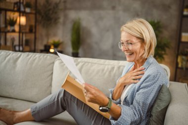 Olgun bir kadın evde çalışıyor. Mektupları iyi haberlerle okuyor.