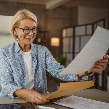 Evde çalışan olgun bir kadın mektubu okuyup, iyi haberlerle birlikte zarfı açar.