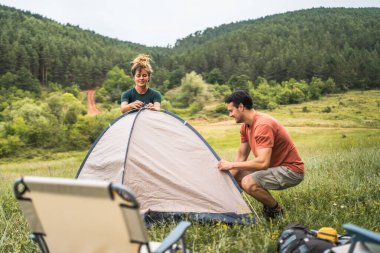 Çift erkek arkadaş ve kız arkadaş kamp için doğada bir çadır kurmuşlar.